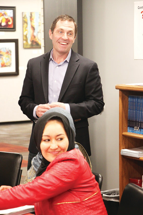 U.S. Rep. Jason Crow stands behind Afghan immigrant Adila Elhem in a citizenship class at the Littleton Immigrant Resource Center on April 15. Crow visited during a challenging time for the center, which lost a federal grant last year and is fighting fears among legal immigrants about pursuing citizenship.