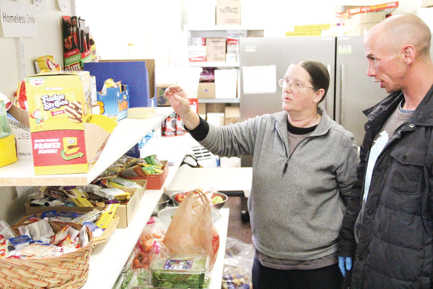 Sandy Nicol, 56, left, helps a client March 17 at the food pantry at Wellspring Anglican Church in Englewood. Nicol is experiencing homelessness but volunteers for others at Wellspring. The client did not want to be named.