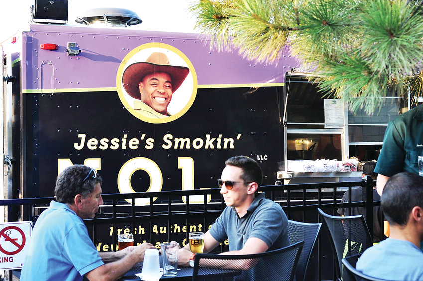 Patrons eat outside the food truck, Jessie’s Smokin’ NOLA, which serves food inspired by New Orleans cuisine.