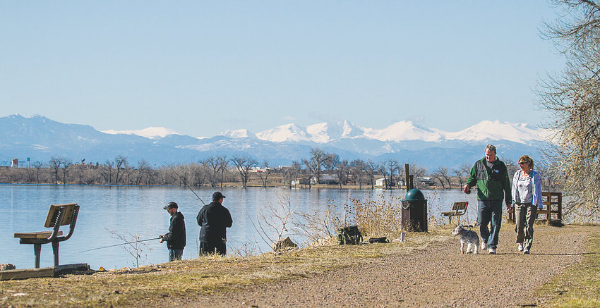 People walk with their dog as others fish at Barr Lake in the Brighton area.