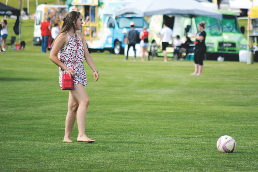 Katherine Lange, 20, of Edwards, Illinois, takes a break from working at booth selling handbags to kick the soccer ball around with friends at Westminster's Fourth of July Celebration at Westminster's City Park.