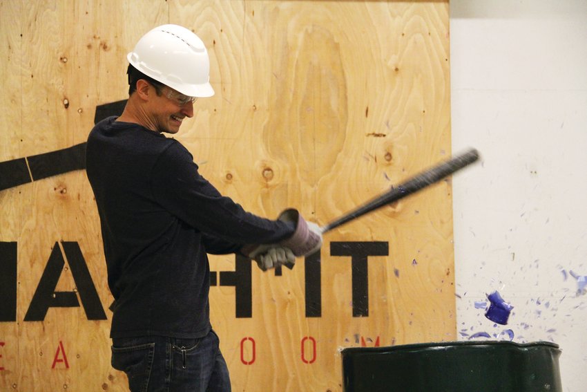 Dustin Gagne, an owner and founder of Smash It Breakroom, shatters a vase with a baseball bat Sept. 24 at his business in west-central Denver.
