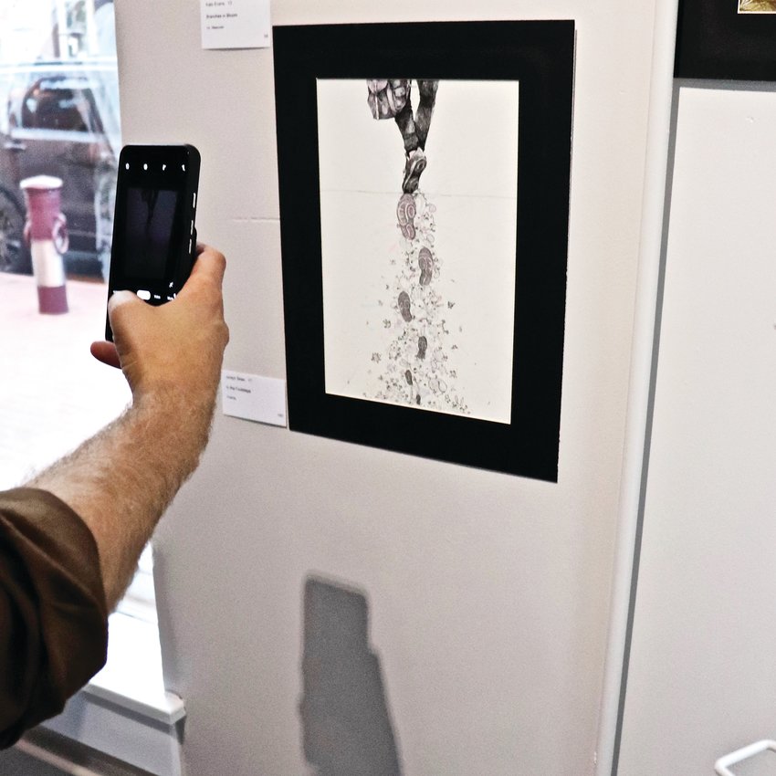 Parson takes a shot of "In the Footsteps" by student Jordyn Shen, which was hung in Vouna, a clothing and accessories store.