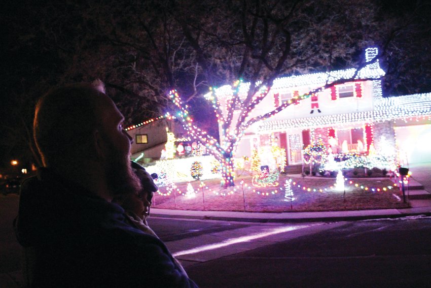 David Martin admires his handiwork carrying his newborn son, Matthew. Martin said he stands there, across the street from his house, to enjoy the full view of his house covered in more than 20,000 light bulbs.
