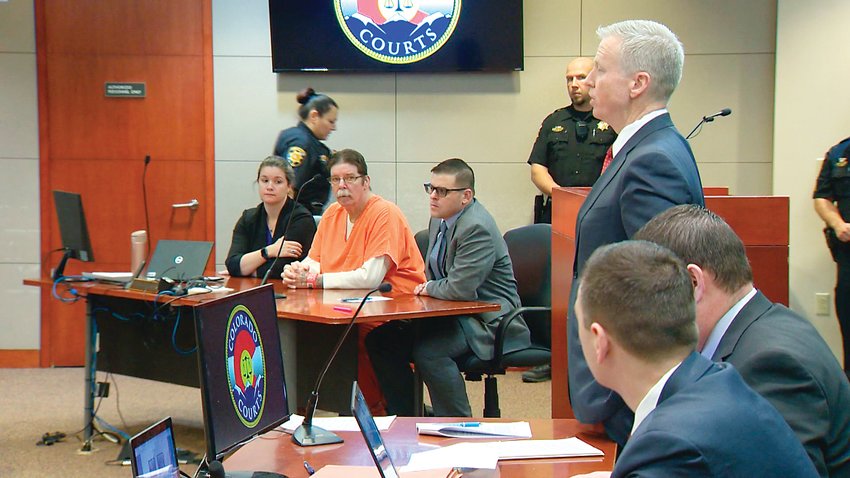 District Attorney George Brauchler addresses the judge during a hearing in the case against James Clanton Feb. 21. Clanton, 62, can be seen in an orange jumpsuit.