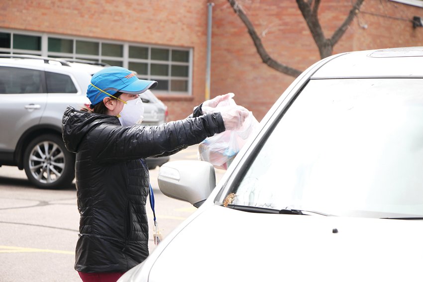 Sarah Kinney passes out meals at East Elementary School in Littleton on March 23. With schools closed because of COVID-19, Littleton Public Schools plans to keep distributing free breakfasts and lunches to all kids under 18 for the foreseeable future.