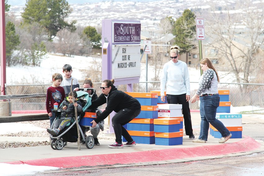 The Douglas County School District’s food services department is receiving assistance from some community partners like churches that are providing boxes of food to families in addition to the breakfasts and lunches the district is providing. Here, a volunteer loads food into the stroller of Jennifer Truhler, who came with her four children to pick up a lunch.