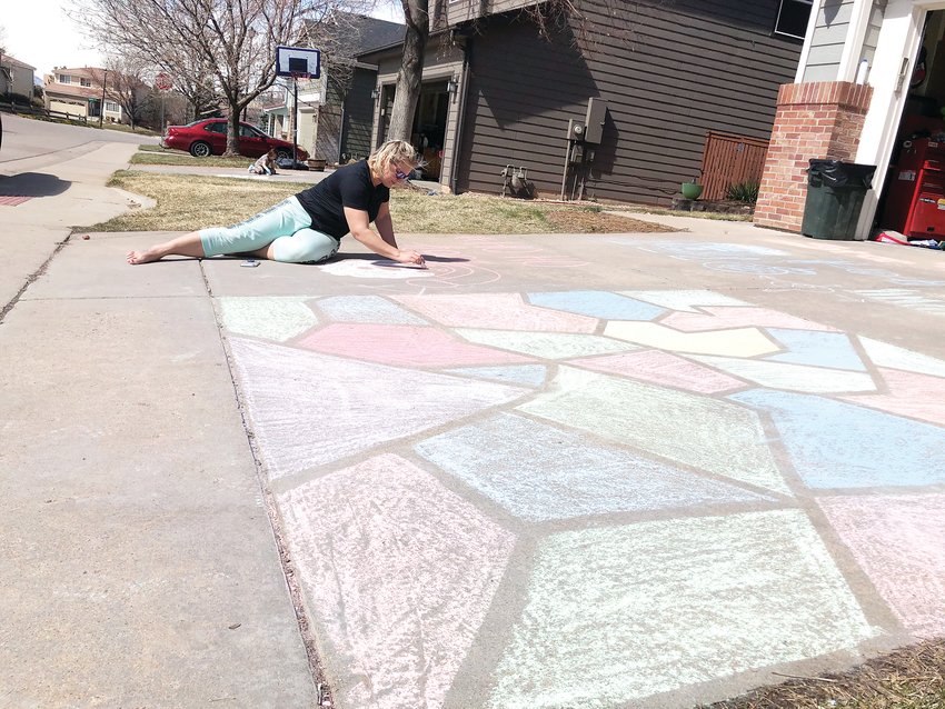 Mandy Henry, 40, works on a chalk drawing of Santa Claus on the driveway of her Highlands Ranch home. Henry's 17-year-old daughter completed the stain-glass style chalk art in the front using painters tape.