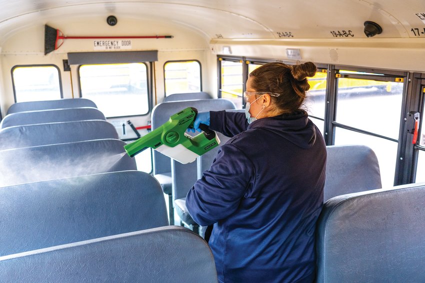 A worker sprays a school bus seat during cleaning procedures in Cherry Creek School District as a precaution against COVID-19.