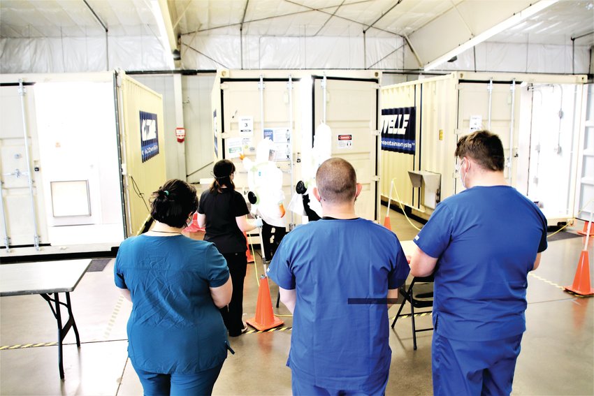 The team at Battelle’s N95 decontamination site in the Adams County Fairgrounds Exhibit Hall prepares to take two boxes of used N95 masks into their decontamination chamber. The masks will be put on a shelf in the chamber, which is filled with hydrogen peroxide vapor to kill any germs or virus. After four hours of treatment, the masks will be returned to the hospital that sent them in.