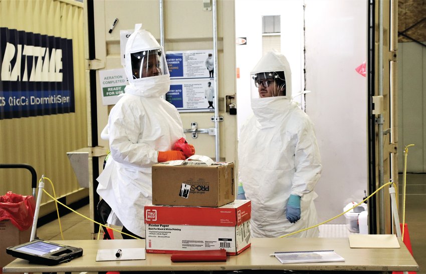 Two workers at the Battelle site in the Adams County Fairgrounds Exhibit Hall prepare to unpack two boxes of used N95 masks, sort them and prepare them to be decontaminated May 14.