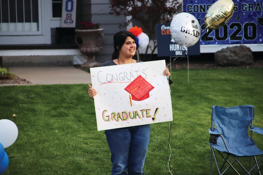 Families cheer on seniors as they walk down the street in a makeshift graduation walk put on by neighbors along Unbridled Avenue in the Canterberry Crossing neighborhood of Parker.