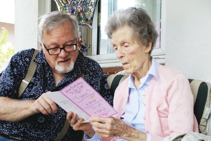 Kerry Ingram, left, reads a birthday card with his mom Margie, who celebrated her birthday with a drive-by party.