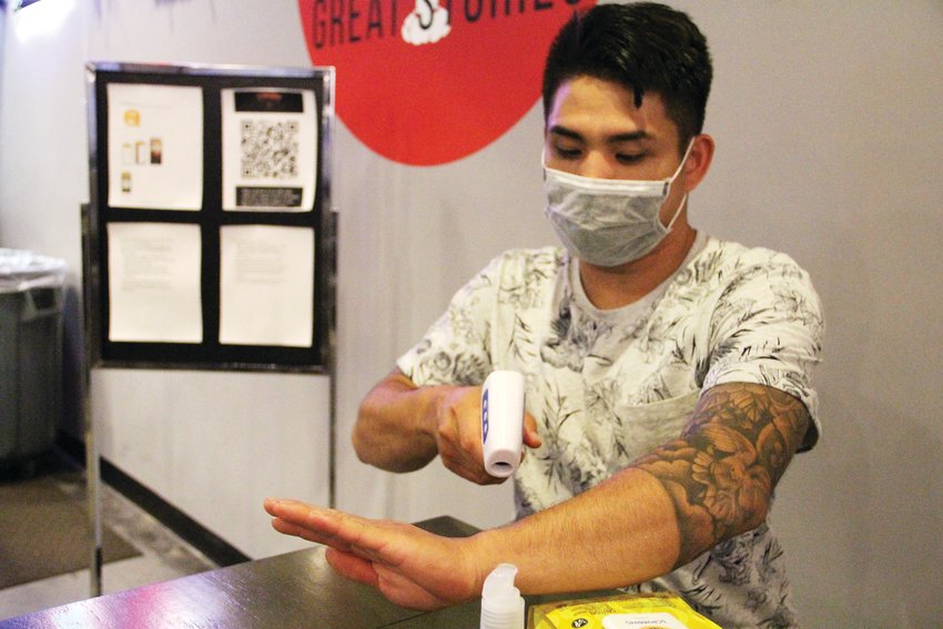 Khiem Nguyen, owner of Crawfish Boil Co. restaurant and bar at The Streets at SouthGlenn, demonstrates on June 4 using a no-contact thermometer — usually, it's pointed at a person's forehead. The tool is one of many supplies the restaurant brought aboard to prevent the spread of COVID-19.