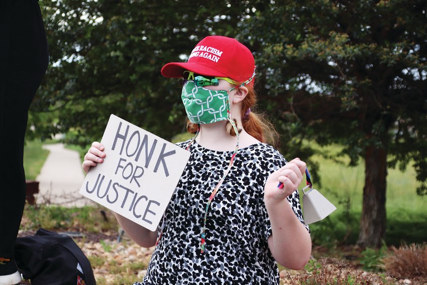 Highlands Ranch resident Kaia Watson, 10, wears a red “Make Racism Wrong Again” hat and carried a “Honk For Justice” sign at an intersection in Highlands Ranch June 8. She also carried a cow bell that she rang throughout the protest.