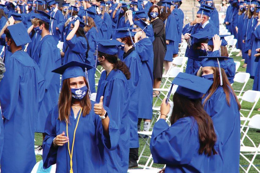A student, bottom left, turns to give the thumbs-up sign as graduates stand for the traditional moving of the tassels on their caps July 27 at Grandview High School’s graduation ceremony.