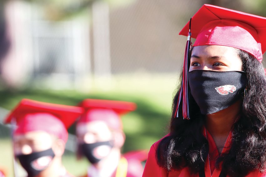 A student sits in the crowd, wearing an Eaglecrest-themed face mask. Many students wore the same type of mask bearing their school’s logo at graduation.