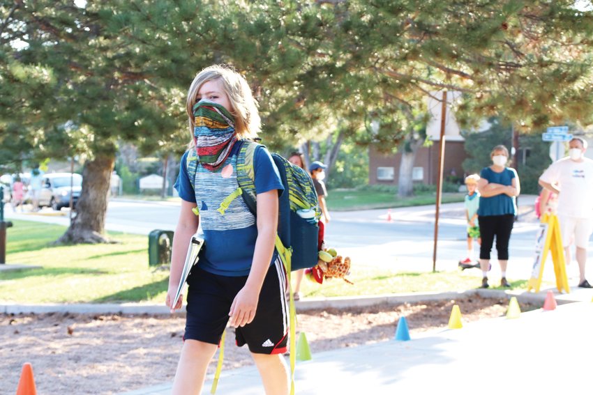 A student strides down a walkway lined with colorful cones and school staff to welcome fifth-graders back to school on Aug. 17. Masks are required in Cherry Creek School District amid the pandemic.