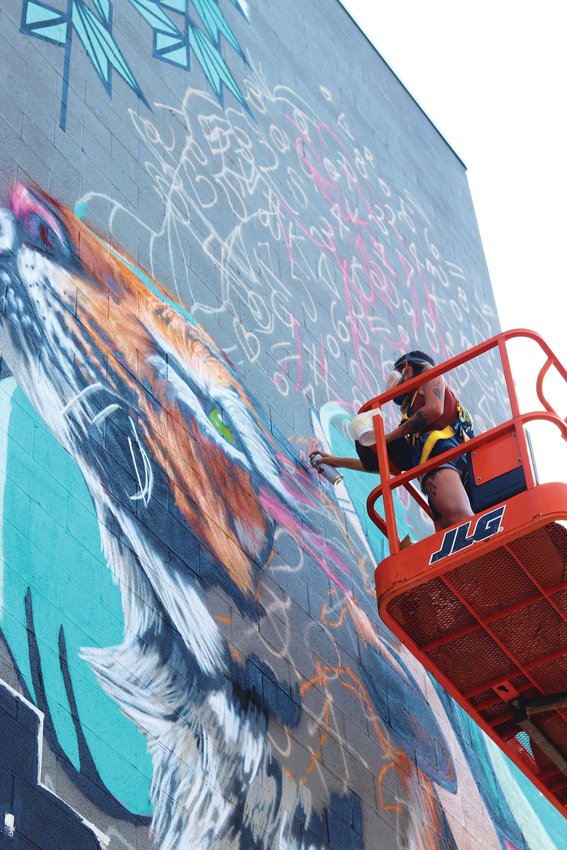 An artist paints a mural of a tiger on the side of a building in Westminster during the Babe Walls mural festival.