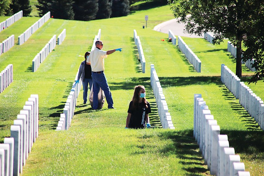 Volunteers cleaning up Fort Logan National Cemetery make their way among the headstones.