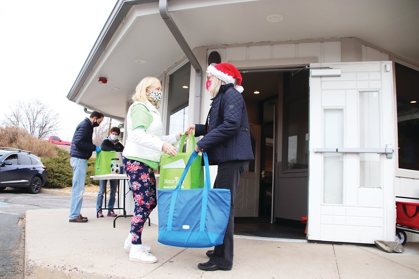 Nourish Meals on Wheels director Diane McClymonds, right, hands off bags of meals to volunteer drivers outside the group's headquarters in south Littleton on Dec. 10.