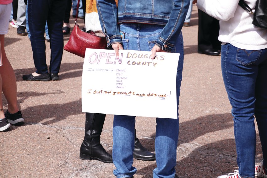 An attendee of a rally in Castle Rock holds an "Open Douglas County" sign. The rally in March gathered a crowd of dozens in support of removing COVID-19 restrictions.