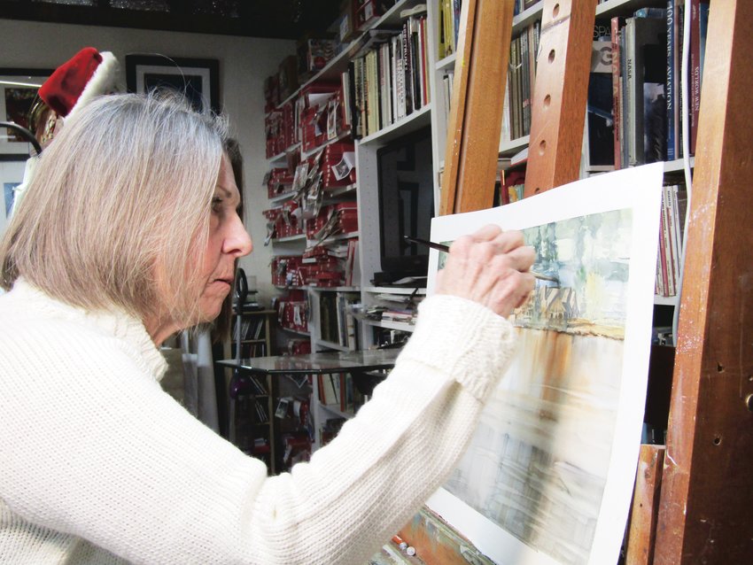 Carol Newsom works on a watercolor painting of the Evergreen Lake House in the couple’s home studio, which is a converted garage.