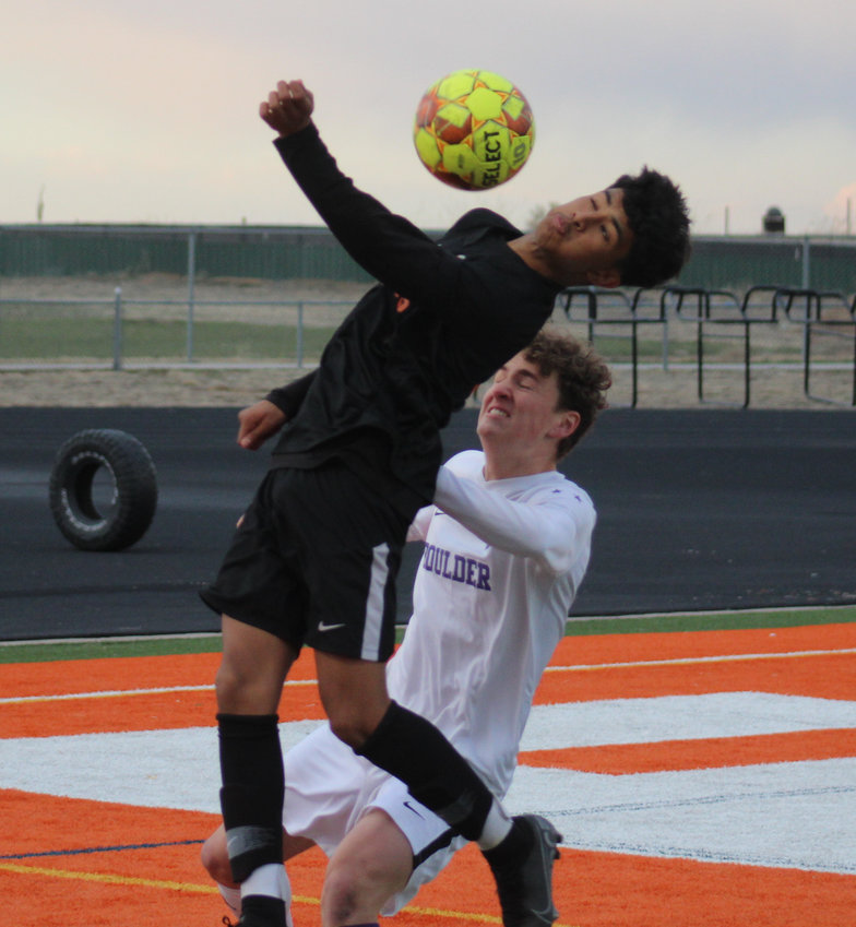 Adams City's Andy Galvan gets to the ball ahead of the onrushing MIcah Garry of Boulder during the first round of the state 5A soccer playoffs April 22.