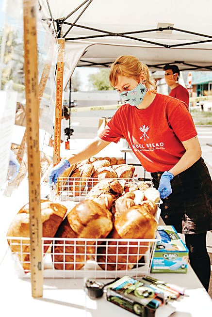 Maya Dank, market director for Rebel Bread, sets the local bakery’s items out for sale during last year’s South Pearl Street Farmers Market. Rebel Bread is looking forward to being a vendor at both the South Pearl Street Farmers Market and the City Park Farmers Market this year.