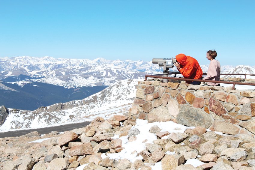 A couple looks through a viewing scope at the summit of Mount Evans Friday. The highway to the summit reopened Friday after being closed since September 2019.