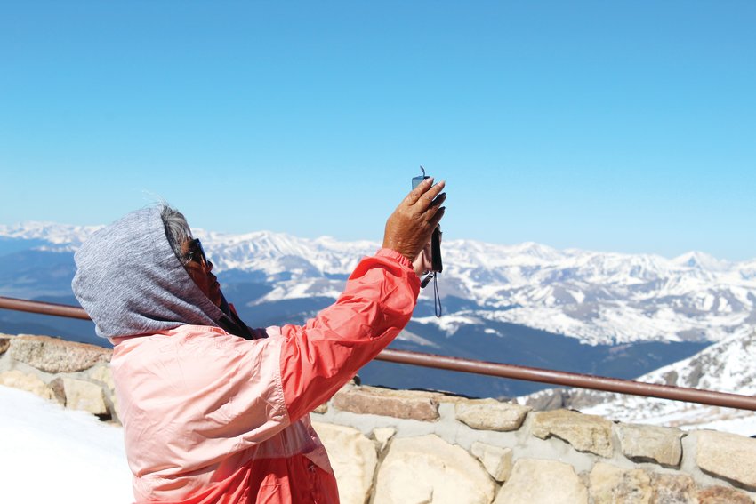 A woman takes a photo of the final summit at the top of the Mount Evans Scenic Byway Friday morning. The top of the highway is a 0.17-mile hike below the mountain's highest point.
