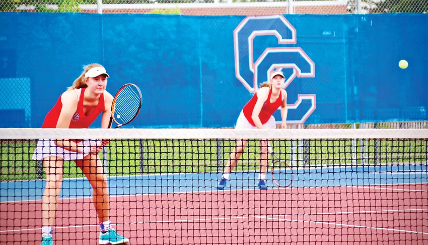 Eliza Hill delivers a serve while sister Nicole waits during the Region 1 qualifying tournament June 1. The Hills won the regional championships at No. 1 doubles and will take a 12-0 record into the June 11-12 state tournament.