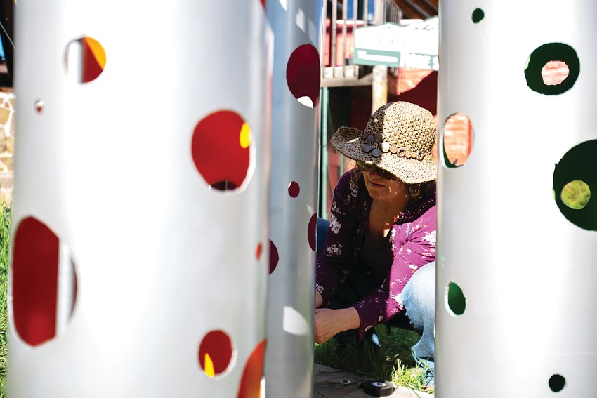 Artist Maureen Hearty fixes lights to her sculpture "Cloud Busters" in downtown Evergreen.