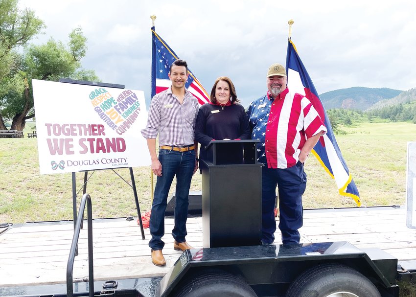 From left, Commissioners Abe Laydon, Lora Thomas and George Teal stand on a stage at a Sandstone Ranch "Together We Stand" event June 26.