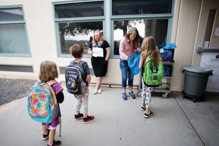 Kristina McCombie and Christine Thompson welcome kids and hand out breakfast as they arrive for summer school at Bergen Meadow.