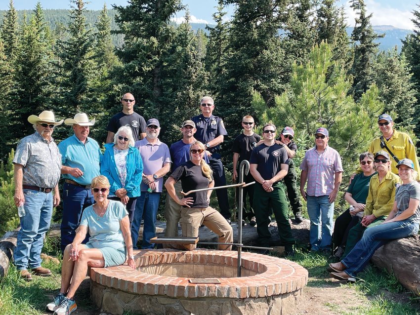 Residents of Indian Creek Ranch and members of Evergreen Fire/Rescue pose around a fire pit ring that EFR had installed to thank the landowners for allowing them to train there for year.