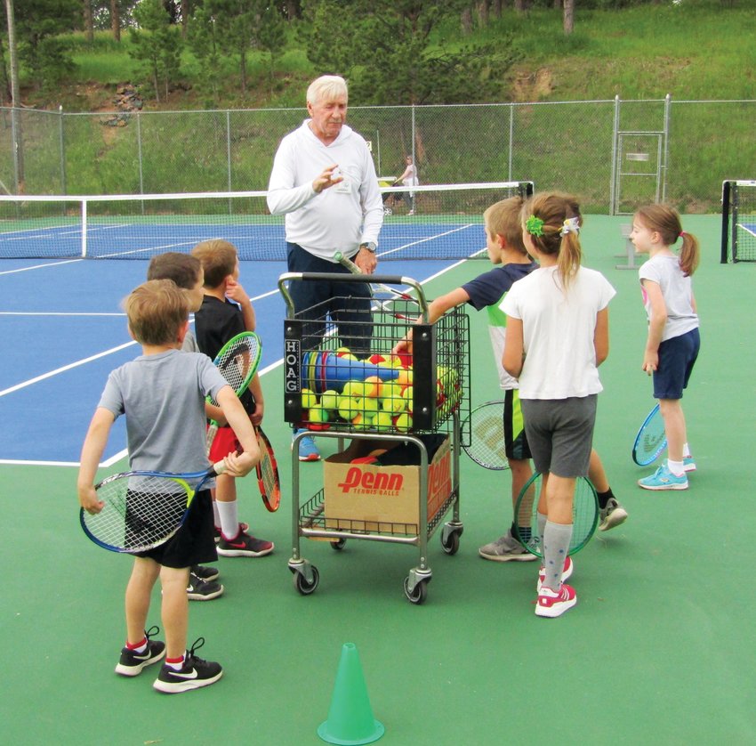 Coach Greg Kyle talks to Evergreen Park &amp; Recreation District tennis camp participants about tennis techniques.