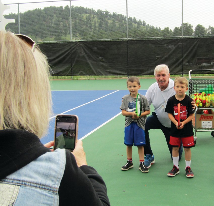 Rhonda Kemmis takes a photo of her grandsons Calvin, 7, and Connor, 5, with coach Greg Kyle after tennis camp.