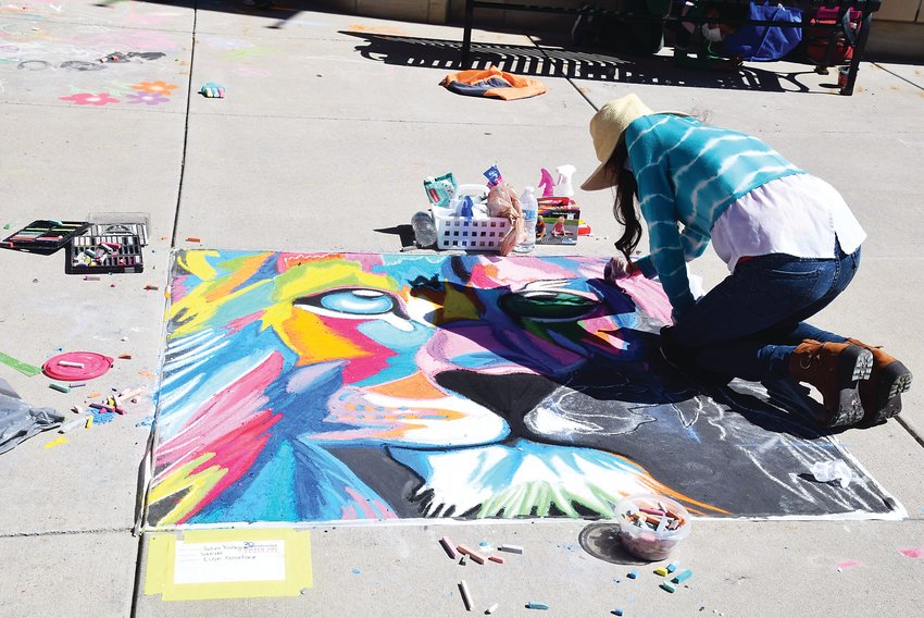 A chalk artist works on a piece at Centennial's celebration at the SouthGlenn outdoor mall.