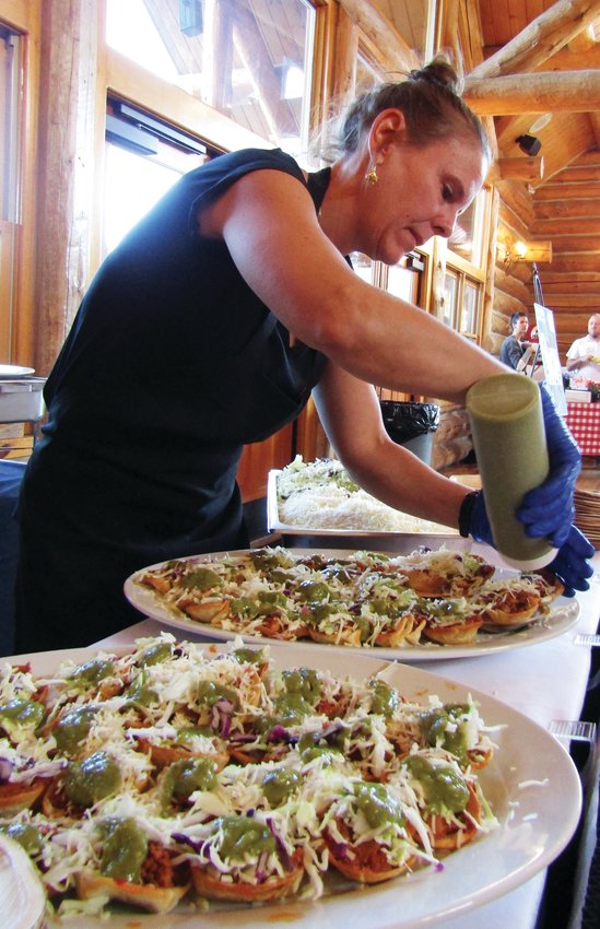 Terry Varyu, owner of Blackbird Café in Kittredge, puts tomatillo sauce on chorizo brunch bites. More than 400 people attended the Taste of Evergreen event.