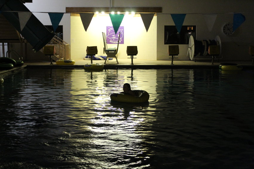 A teen floats on an innertube during the Oct. 15 Rec Center Takeover. The rec center screened “Hocus Pocus” on a large poolside screen, and teens moved between the pool, the silent disco and intention stick station during the event.