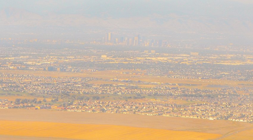 Haze obscures the Denver skyline as seen in an aerial view.