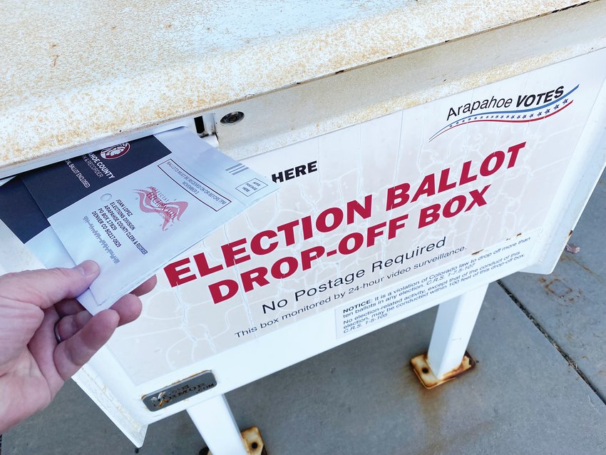 A voter drops off ballots at a ballot box in Centennial.