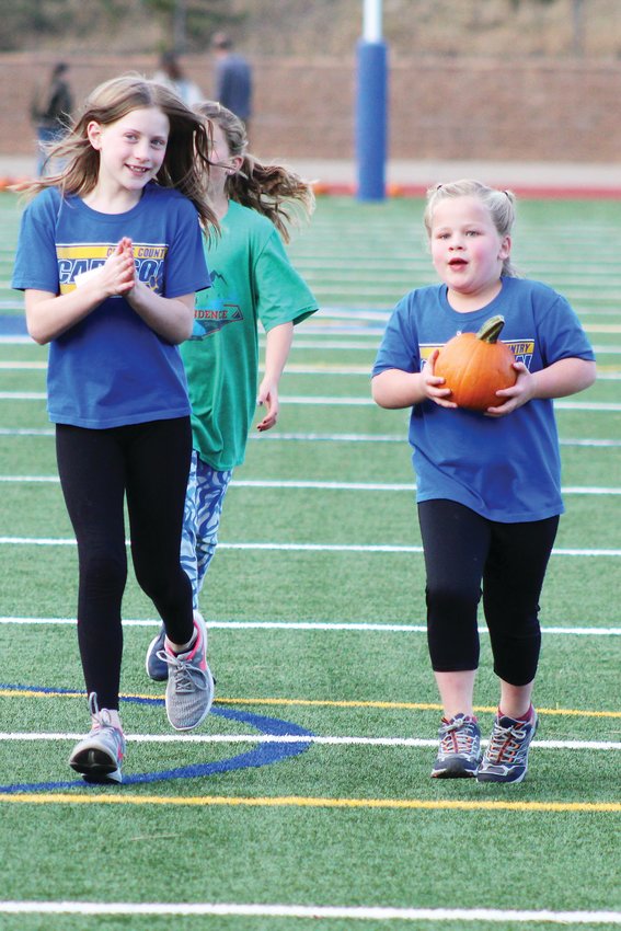 Ciaira Desarno, left, cheers on fellow Carlson Elementary student Mischa Simeonoff as she runs the final stretch of the Oct. 22 Pumpkin Run at Clear Creek High School. The Pumpkin Run was the final race of the year for King-Murphy and Carlson elementary schools’ combined cross country club.