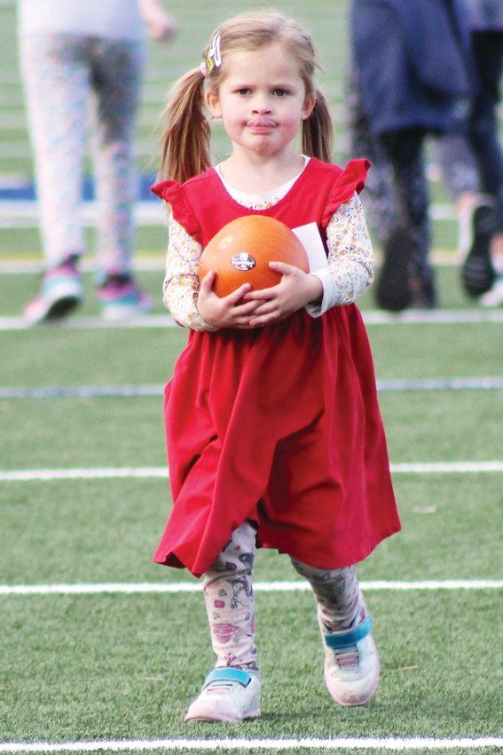 Fiona Robb, a kindergartner at King-Murphy Elementary School, carries a pumpkin for the final stretch of the Oct. 22 Pumpkin Run at Clear Creek High School. Kindergarten and first grade runners completed a lap around the track, grabbed a pumpkin, and then carried it to the finish line at the other end of the field.