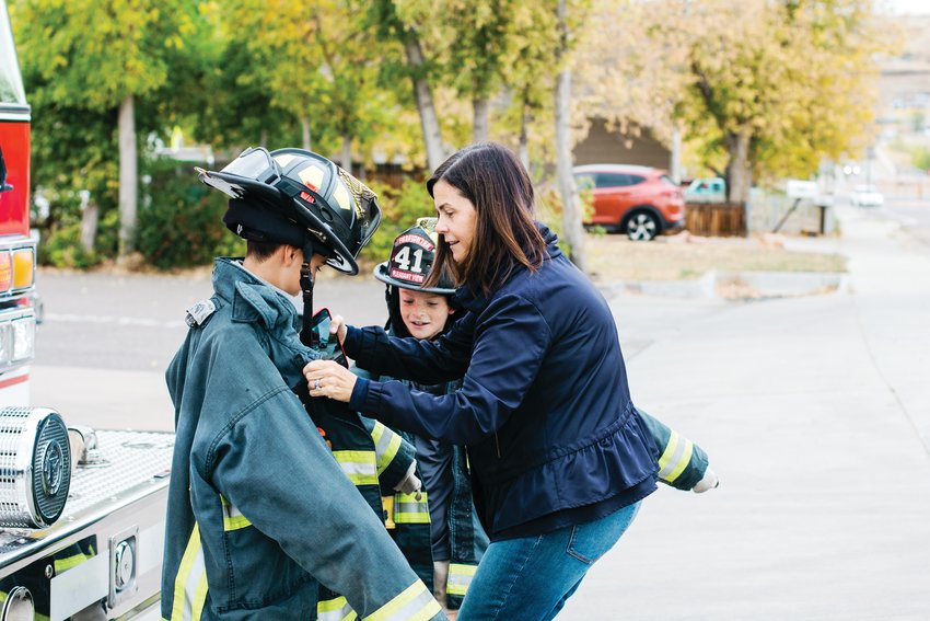 Demetrios Fefes’ sons try on some Pleasant View firefighting gear with a little bit of help from their mom, Kristen at a thank you celebration.