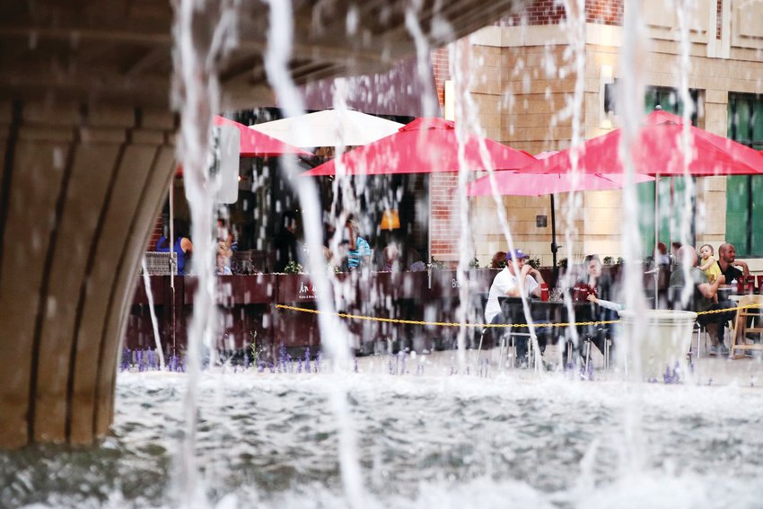 In a 2020 file photo, diners are seen through water falling from The Streets at SouthGlenn’s fountain.