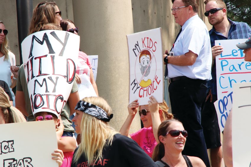 A crowd protests Tri-County Health Department's initial, mid-August requirement for mask wearing in schools on Aug. 30 at the Arapahoe County administration building in Littleton. A sign pictured read, "My kids my choice."
