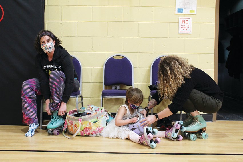 From left, Idaho Springs' Cris Slaymaker puts on her skates while Kerry Slaymaker, 4, is helped by staff member Samantha Dhyne during the Jan. 8 indoor rollerskating session at the rec center. This year, the district will host indoor rollerskating sessions every Saturday from 10:30 a.m.-noon.