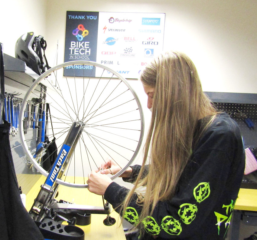 Senior Wyatt Brent adjusts a bike wheel during class.